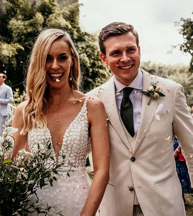 Young man and woman couple celebrating marriage with a white low cut dress and beige suit with blue tie.