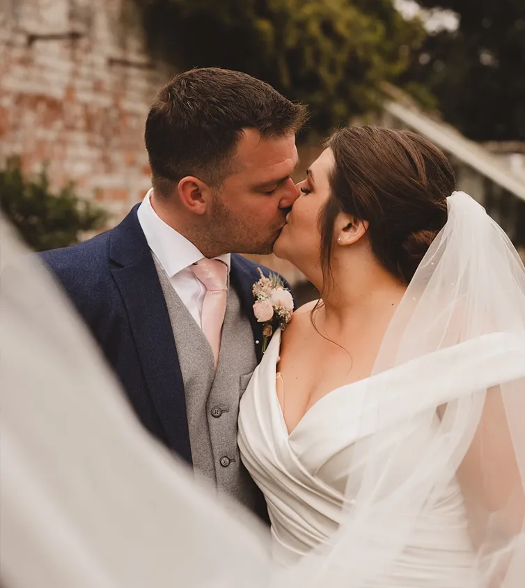 A woman wearing a beautiful white wedding dress holding flowers and a man in a white suit with a bright green tie.